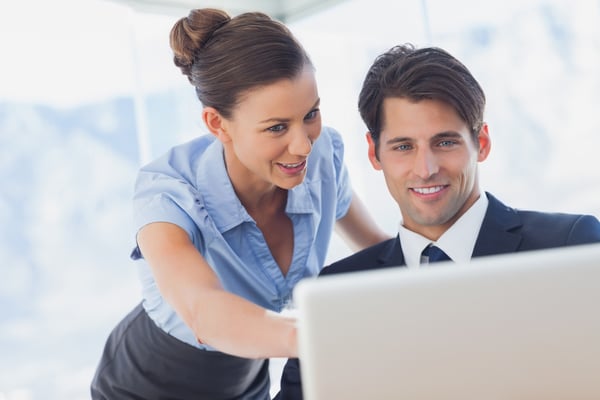 Happy business people looking together at the laptop in the office