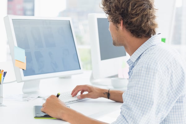 Side view of a male artist drawing something on graphic tablet with pen